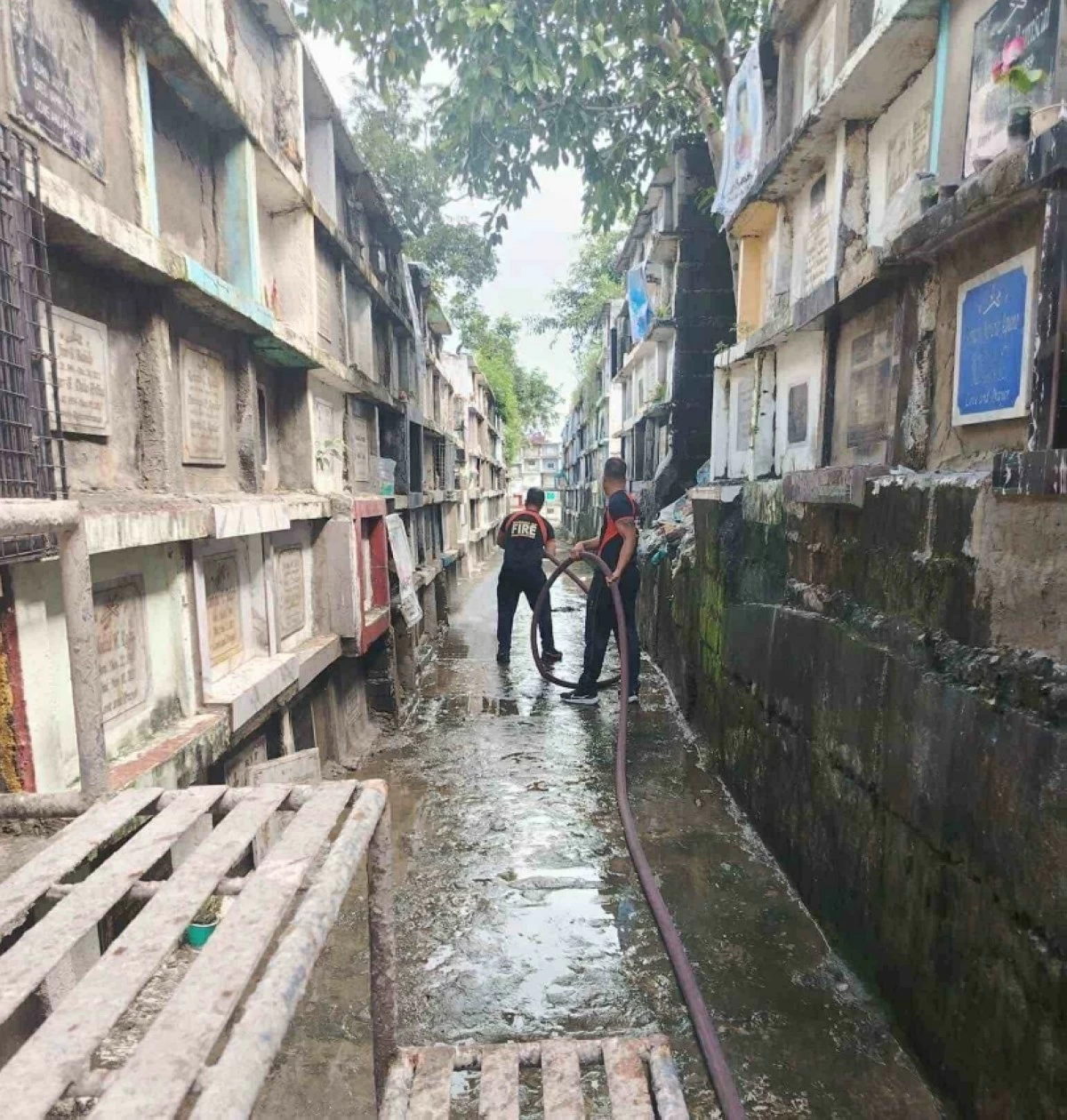 Personnel from the Muntinlupa Bureau of Fire Protection conduct flushing operations in a cemetery. (Photo from Muntinlupa PIO)