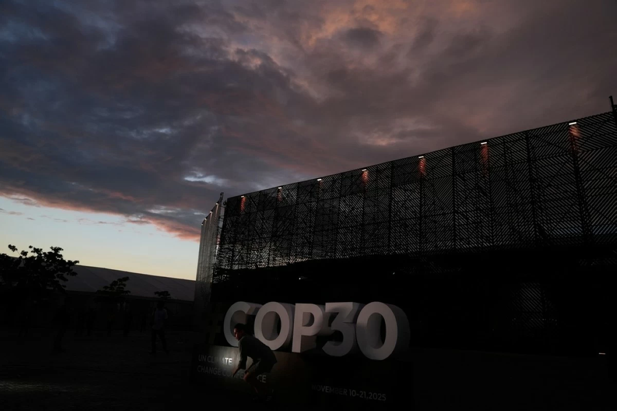 A person poses outside the venue for the COP30 U.N. Climate Summit as the sun sets on Saturday, Nov. 8, 2025, in Belem, Brazil. (AP Photo/Fernando Llano)
