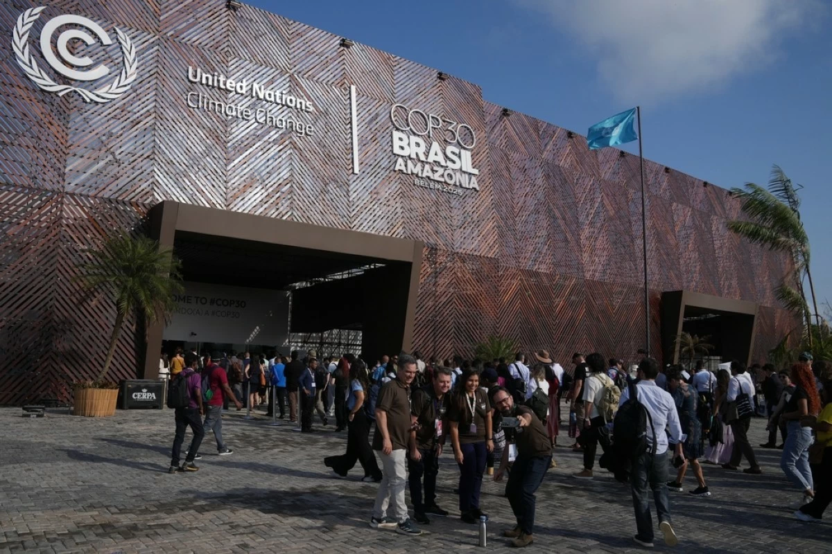 People pose for photos outside the venue for the COP30 U.N. Climate Summit, Monday, Nov. 10, 2025, in Belem, Brazil. (AP Photo/Fernando Llano)