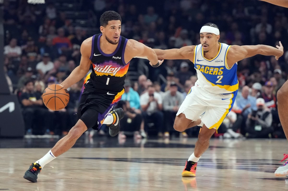 Phoenix Suns guard Devin Booker (1) drives on Indiana Pacers guard Andrew Nembhard during the first half of an NBA basketball game, Thursday, Nov. 13, 2025, in Phoenix. (AP Photo/Rick Scuteri)