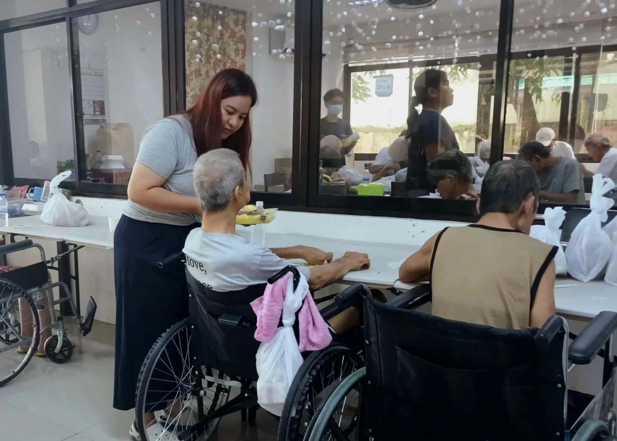 Ms. Abegail Mae Pastor helps an elder with their meal at One Cainta Sunset Retreat. (Photos by Richielyn Canlas)