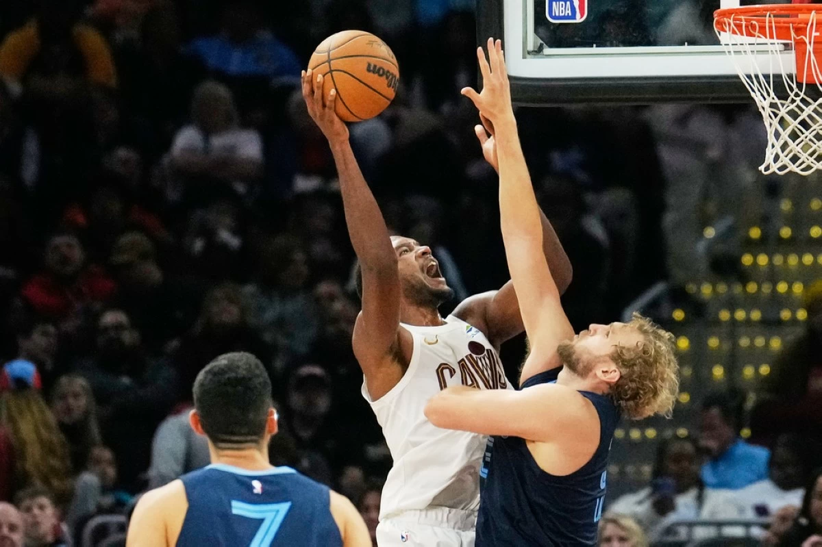 Cleveland Cavaliers center Evan Mobley, left, shoots as Memphis Grizzlies center Jock Landale, right, defends in the second half of an NBA basketball game Saturday, Nov. 15, 2025, in Cleveland. (AP Photo/Sue Ogrocki)
