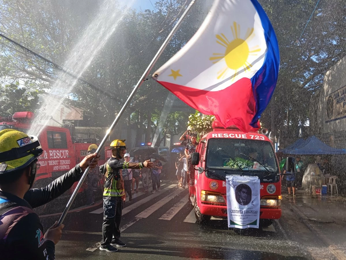 A volunteer fireman waves a flag as the funeral procession passes by. (Photo by Nel Andrade/Manila Bulletin)