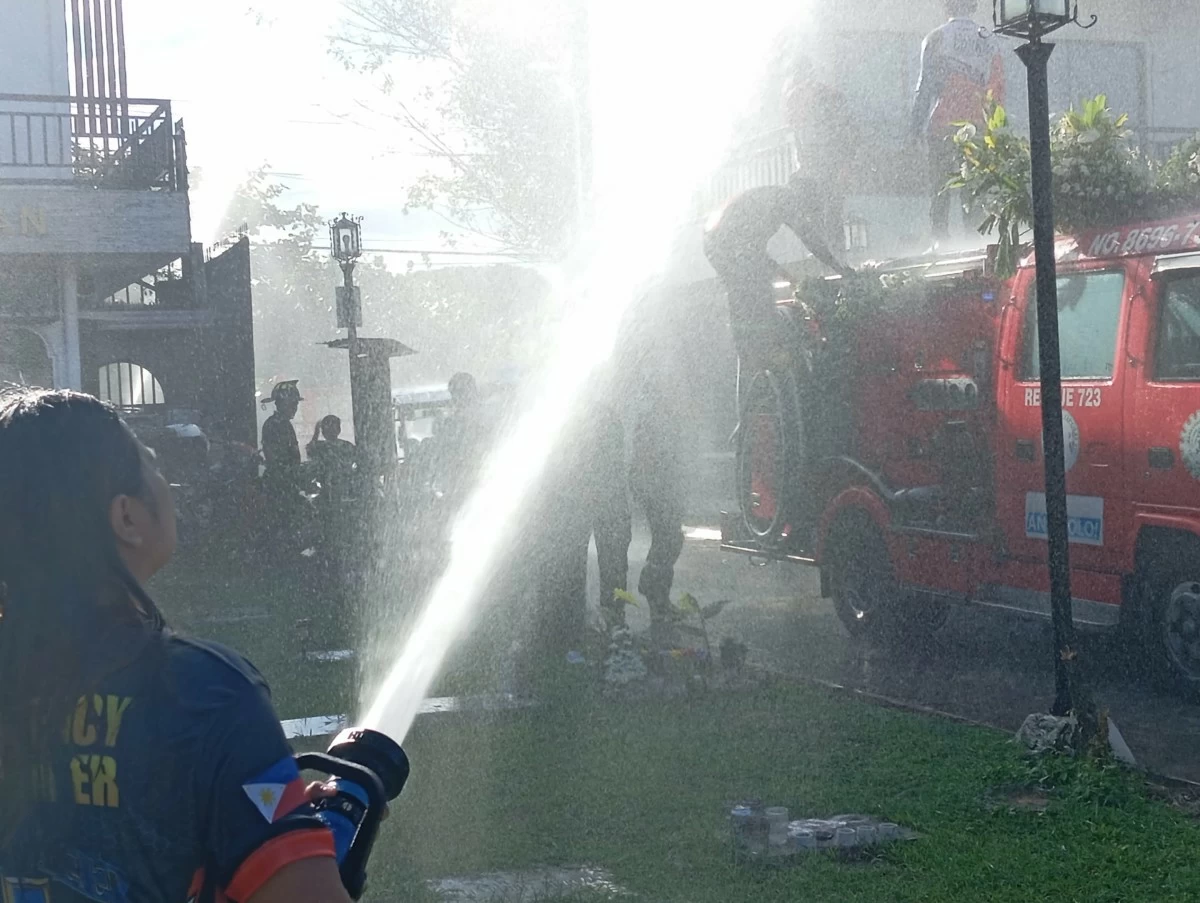 A lady firefighter aims the water from the hose she is holding as a salute to a fallen co-firefighter