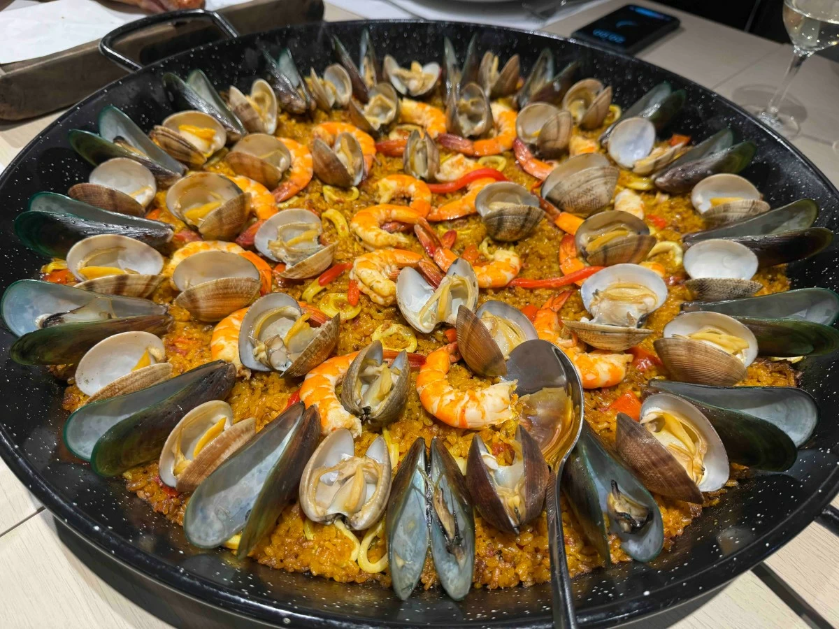 SEAFOOD SPREAD A generous pan of paella filled to the brim with mussels, squid, and shrimp, bringing a bright, briny richness to the table.