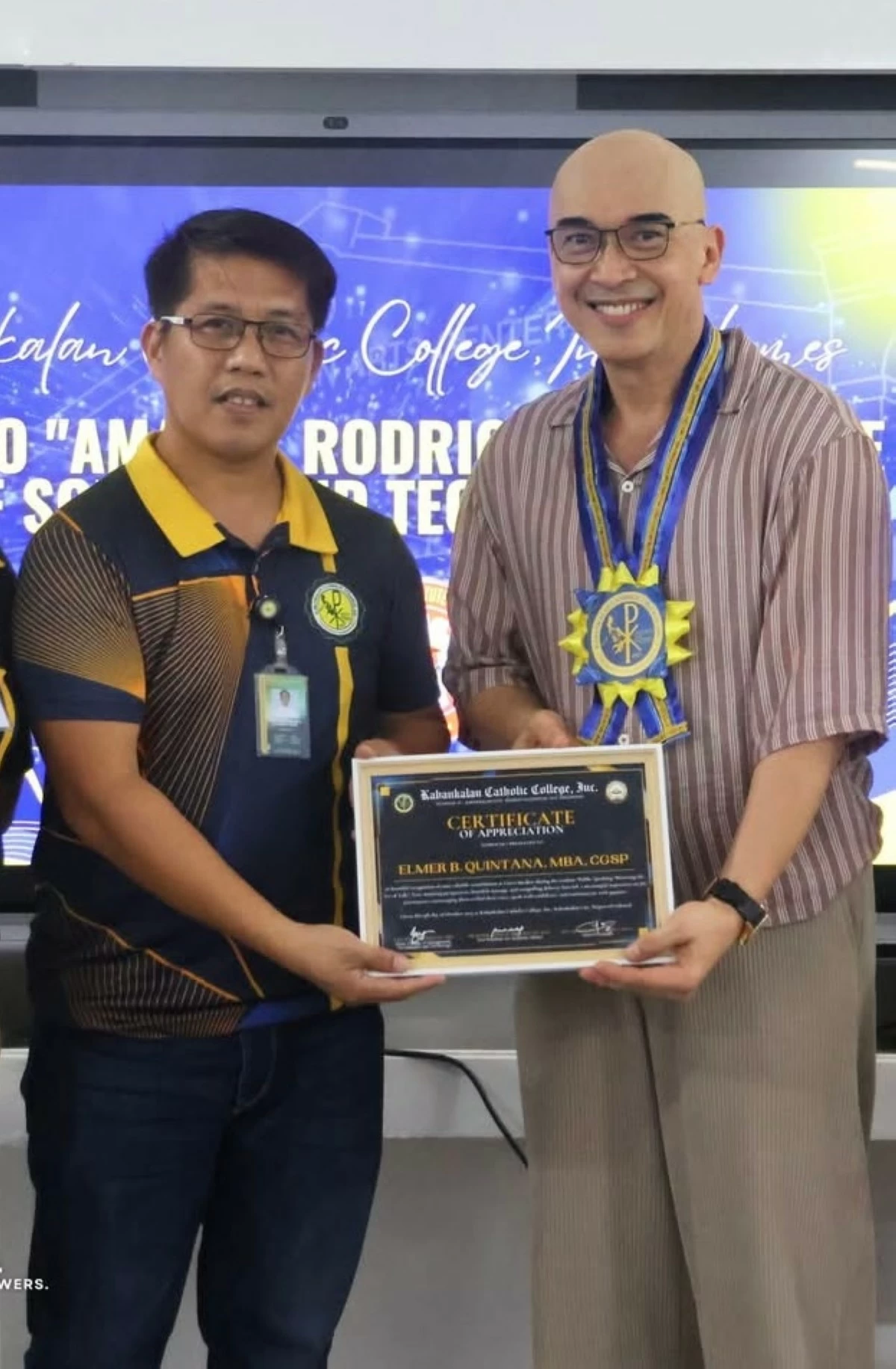 Bong Quintana with Kabankalan Catholic College, Fr. Richard La Chica during the awarding of the certificate of recognition.