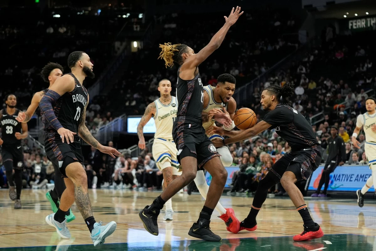 Milwaukee Bucks' Giannis Antetokounmpo controls the ball as he drives between Brooklyn Nets' Noah Clowney, left, and Ziaire Williams, right, during the first half of an NBA basketball game Saturday, Nov. 29, 2025, in Milwaukee. (AP Photo/Aaron Gash)
