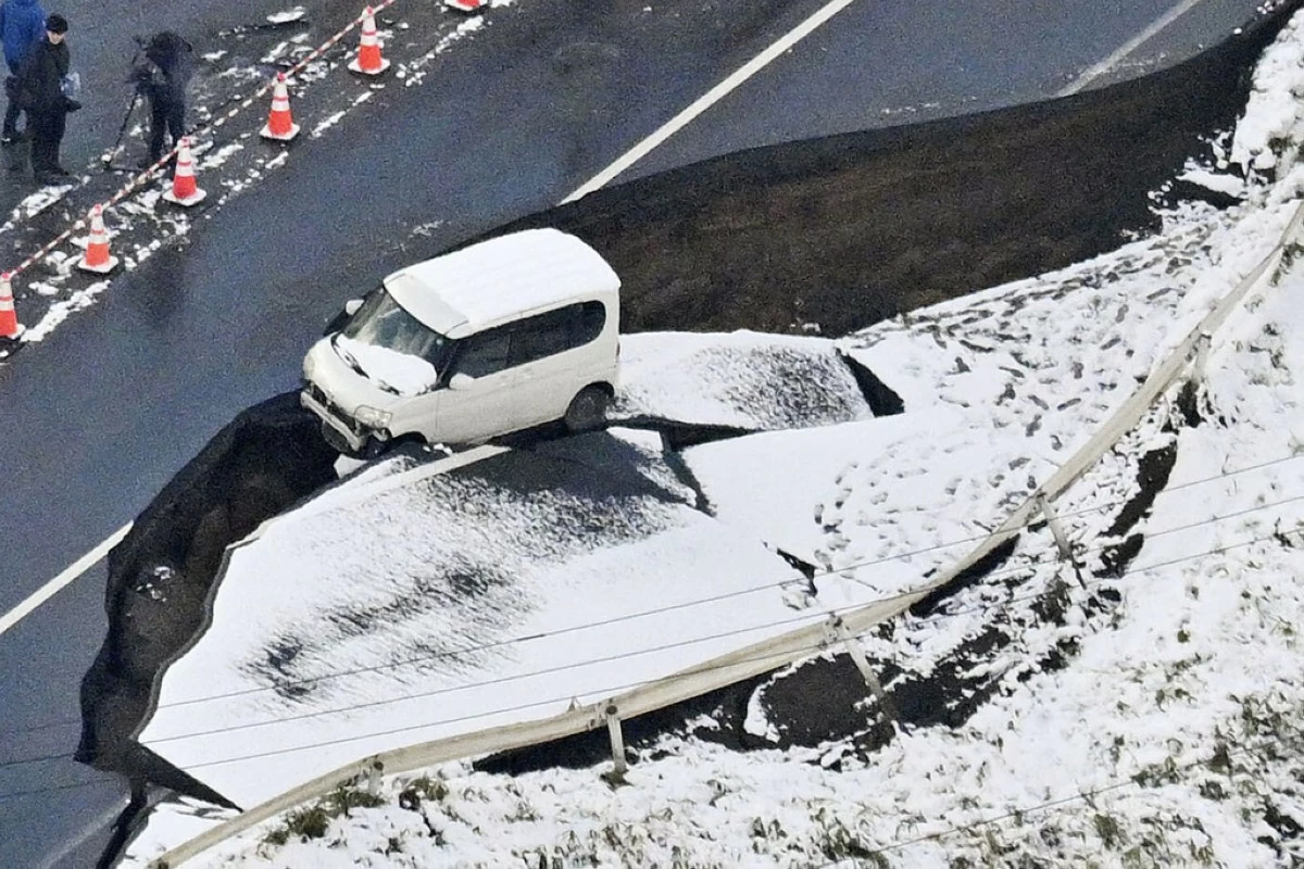 This aerial photo shows a vehicle sitting on a damaged road in Tohoku town, Aomori prefecture, northern Japan Tuesday, Dec. 9, 2025, following a powerful earthquake on late Monday. (Kyodo News via AP)