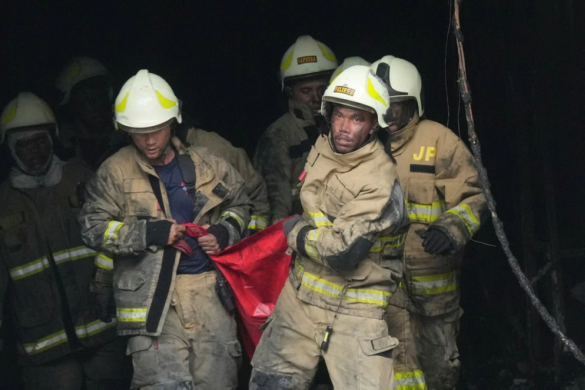 Rescuers carry out the body of a victim from the site of a fire in Jakarta, Indonesia, Tuesday, Dec. 9, 2025. (AP Photo/Dita Alangkara)