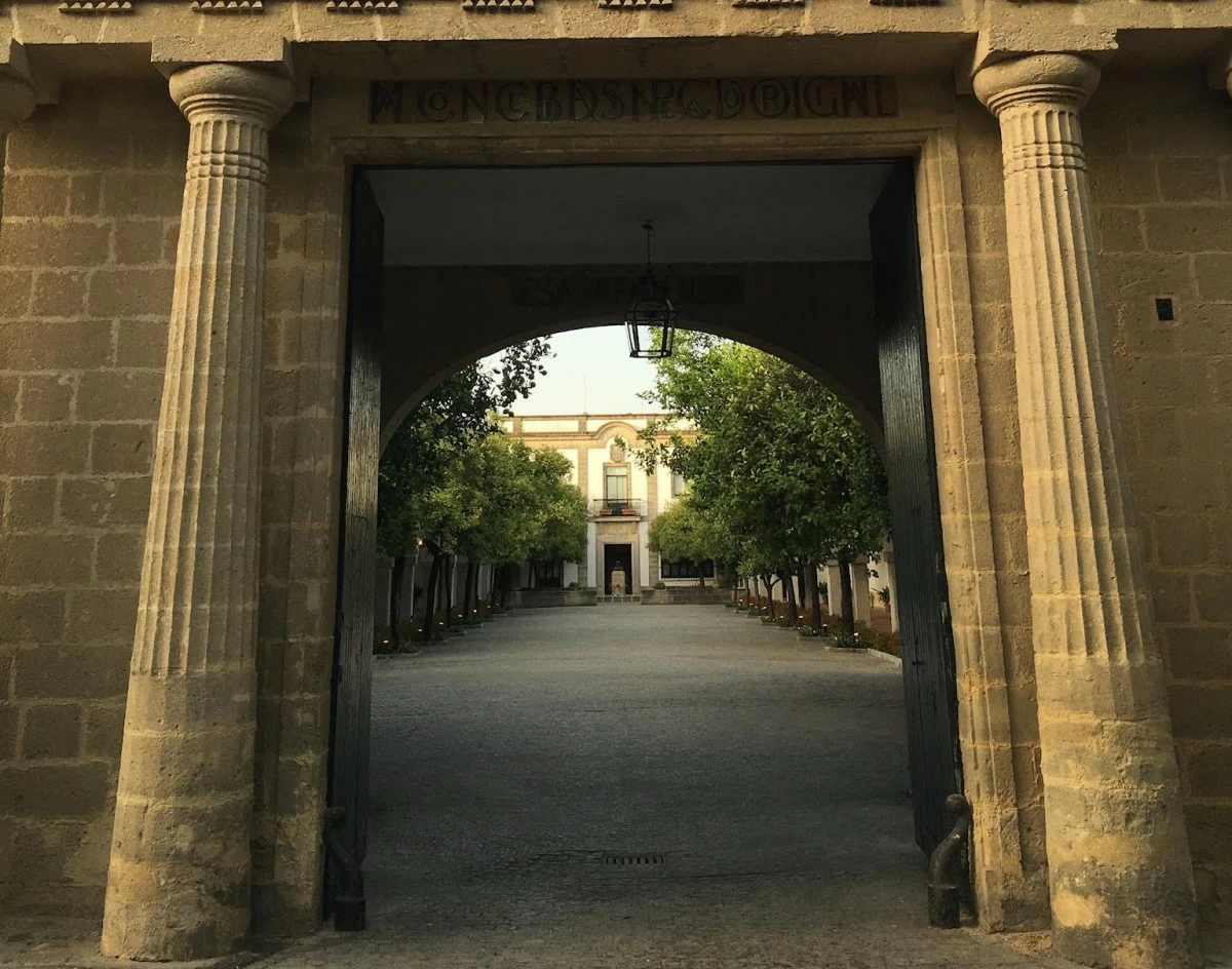 Framed by ancient stone pillars, the stately entrance to Bodegas Fundador reveals the serene beauty of the courtyard beyond.