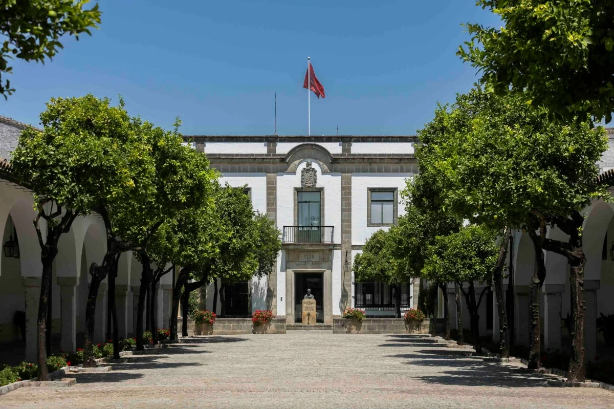 Beneath the bright Andalusian sun, the classic white facade and symmetrical orange trees of Bodegas Fundador&#039;s central courtyard offer a serene retreat.