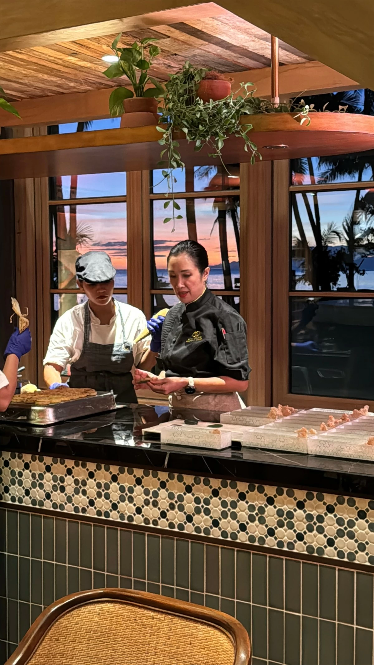 SUNSET SERVICE Chef Bettina Arguelles at work inside Tiya’s House, framed by the purple-hued sunset of Panglao Beach beyond the window