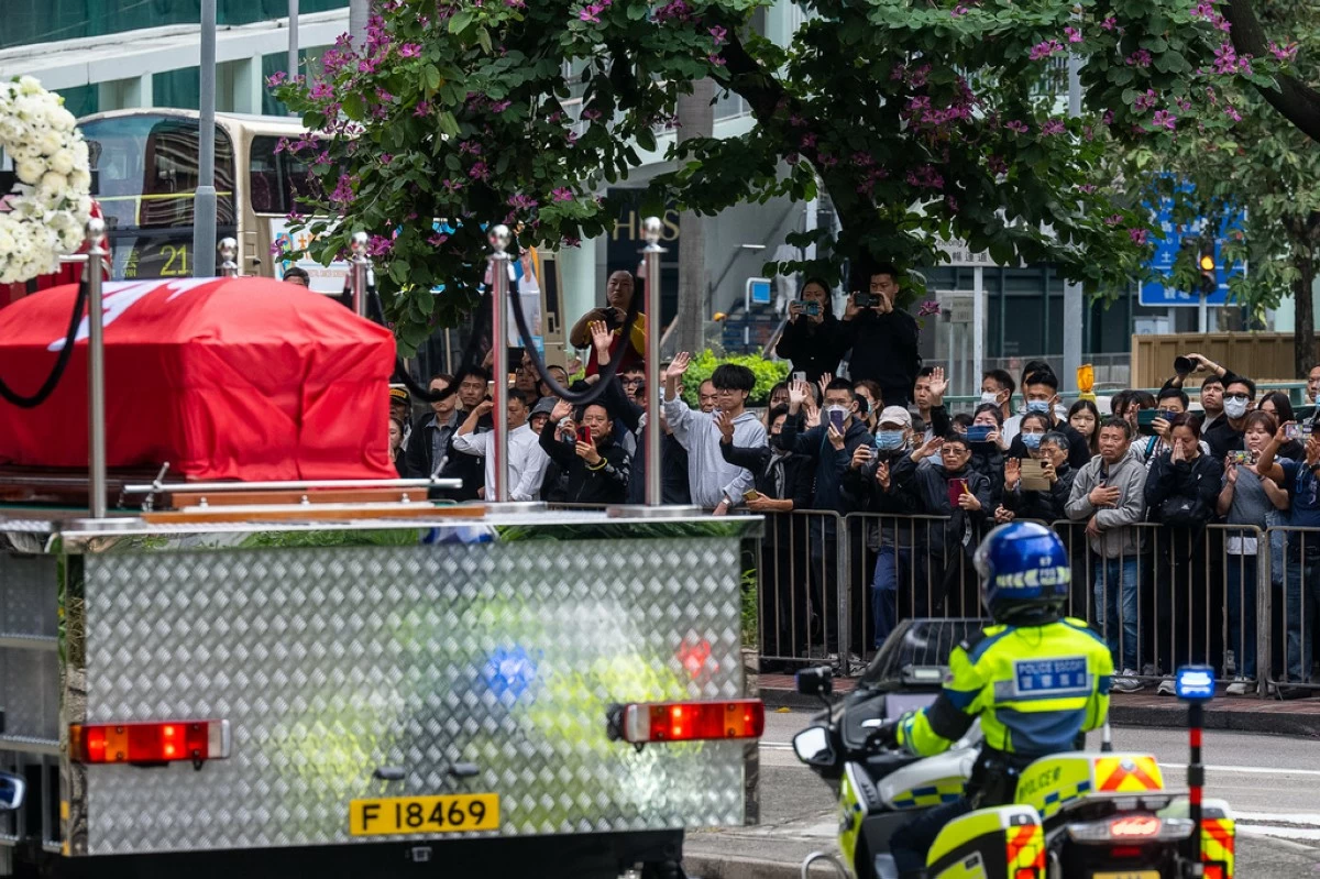People gather outside a funeral parlor to pay tribute to Ho Wai-ho, the firefighter who lost his life in the line of duty during the deadly fire at Wang Fuk Court on Nov. 26, passing by a funeral parlor in Hong Kong, Friday, Dec. 19, 2025. (AP Photo/Chan Long Hei)