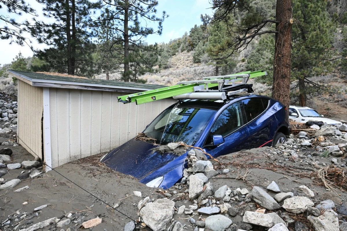 A car is buried in mud after a series of storms Thursday, Dec. 25, 2025, in Wrightwood, Calif. (AP Photo/William Liang)