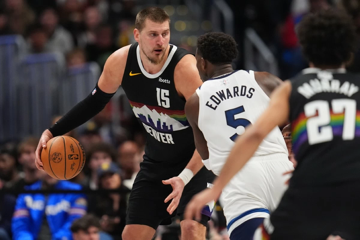 Denver Nuggets center Nikola Jokić, back, looks to pass the ball as Minnesota Timberwolves guard Anthony Edwards defends in overtime of an NBA basketball game Thursday, Dec. 25, 2025, in Denver. (AP Photo/David Zalubowski)