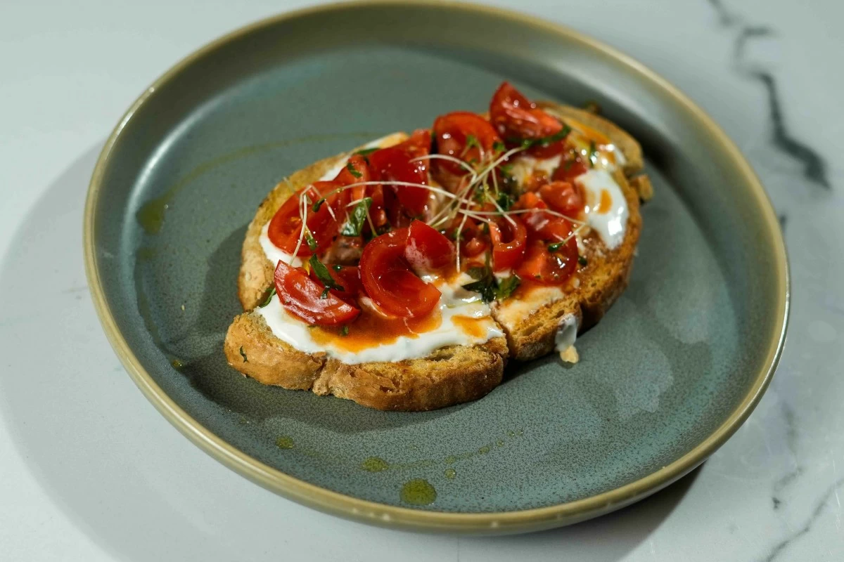 SIMPLE PLEASURES Bruschetta topped with fresh tomatoes, goat cheese whip, premium EVOO and grilled sourdough toast.