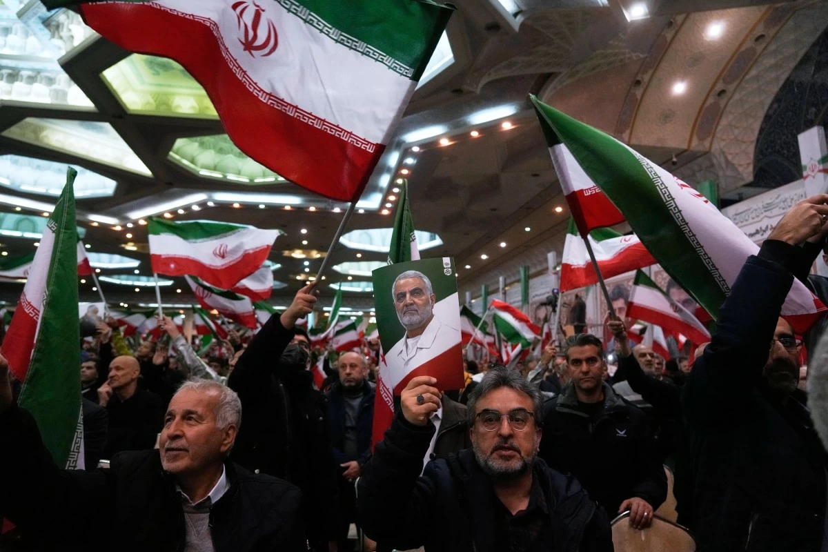 PEOPLE wave Iranian flags as one of them holds up a poster of the late commander of the Iran Revolutionary Guard expeditionary Quds Force, Gen. Qassem Soleimani, who was killed in a US drone attack in 2020 in Iraq, during a ceremony commemorating his death anniversary at the Imam Khomeini grand mosque in Tehran, Iran, Thursday, Jan. 1, 2026. (AP)
