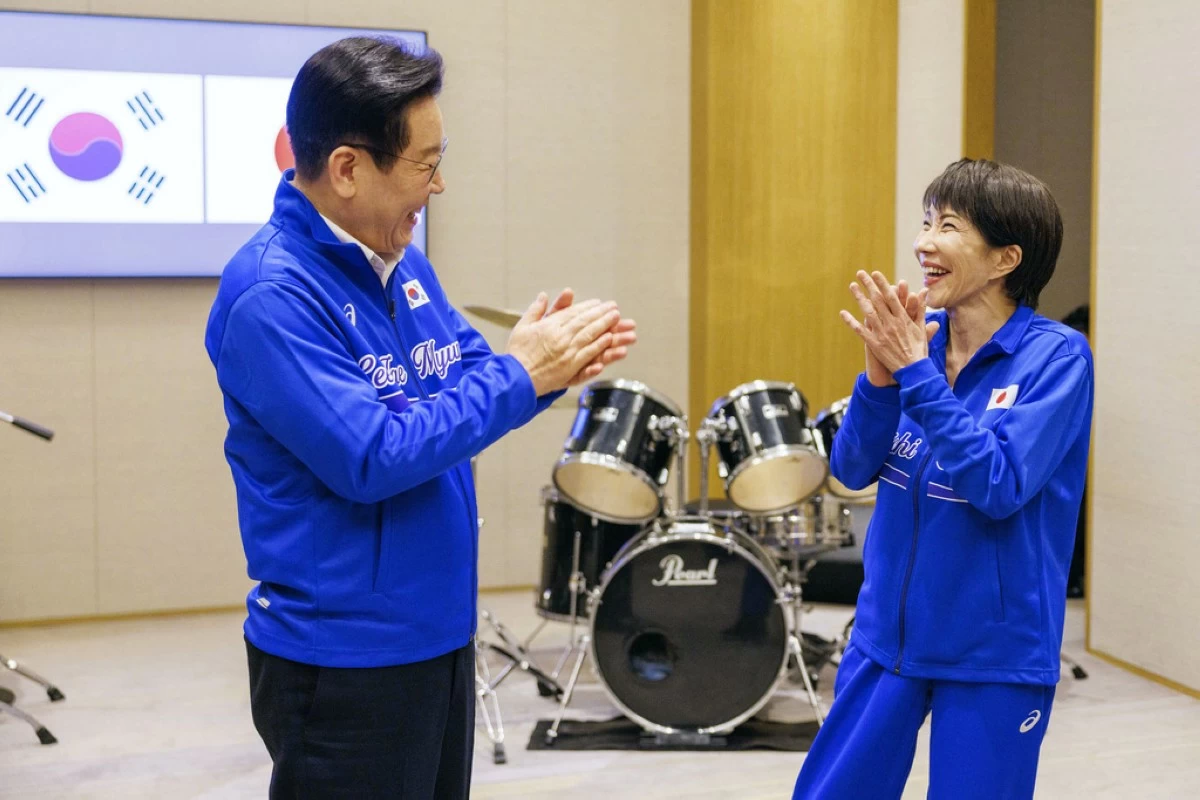 In this photo released on the official website of Prime Minister's Office of Japan, Japanese Prime Minister Sanae Takaichi, right, and South Korean President Lee Jae Myung react as they play drump together after their talks in Nara, western Japan Tuesday, Jan. 13, 2026.  (Cabinet Public Affairs Office via AP)