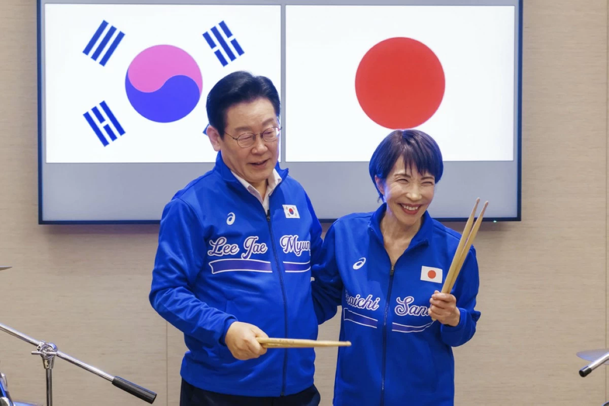 In this photo released on the official website of Prime Minister's Office of Japan, Japanese Prime Minister Sanae Takaichi, right, and South Korean President Lee Jae Myung react as they play drump together after their talks in Nara, western Japan Tuesday, Jan. 13, 2026.  (Prime Minister's Office of Japan via AP)