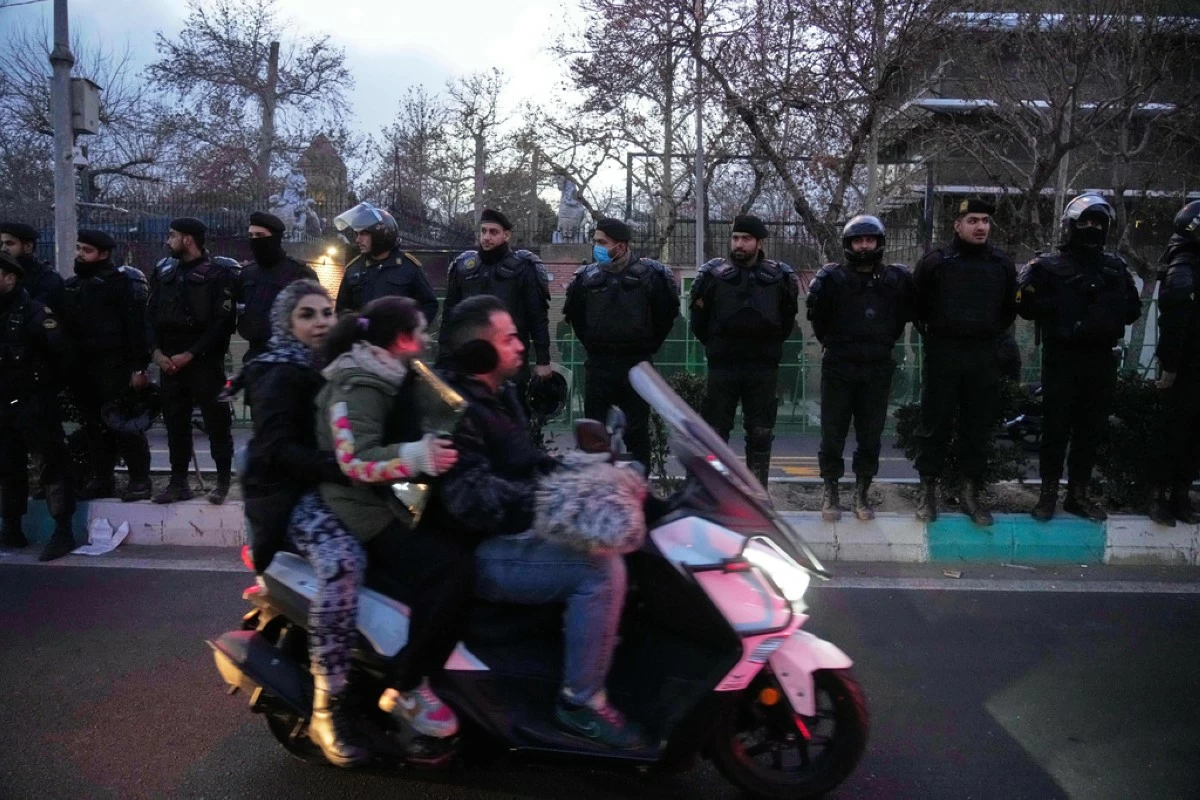 Policemen protect the British Embassy during a protest by hardline supporters of the Iranian government, as people ride on their motorbike in Tehran, Iran, Wednesday, Jan. 14, 2026. (AP Photo/Vahid Salemi)