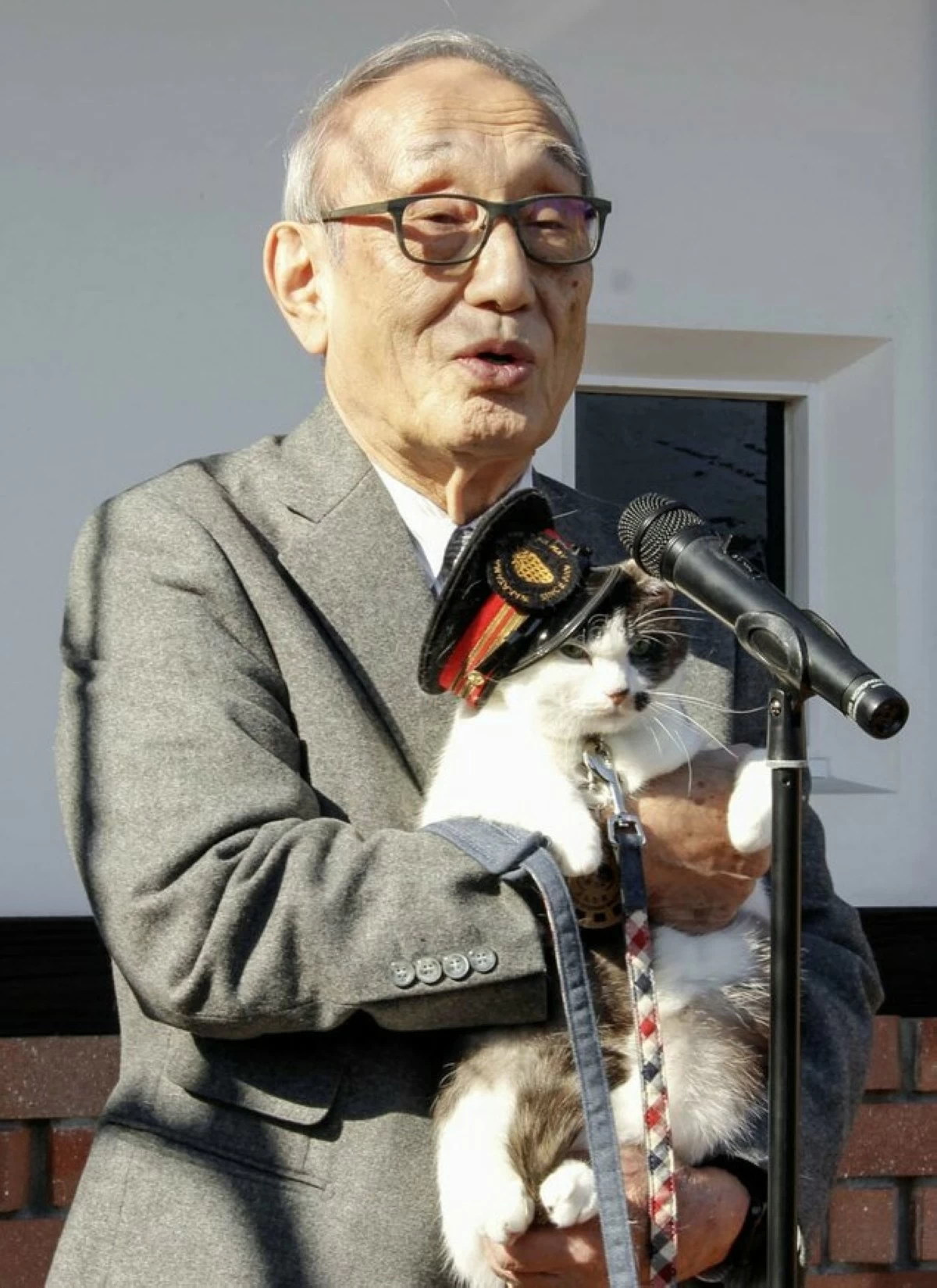 READY FOR DUTY Wakayama Electric Railway Co. president Mitsunobu Kojima presents the newly appointed cat stationmaster Yontama. (Photo Wakayama Electric Railway Company)