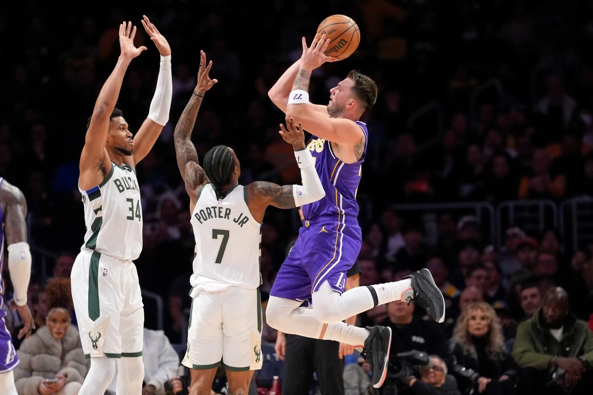 Los Angeles Lakers guard Luka Doncic, right, shoots as Milwaukee Bucks forward Giannis Antetokounmpo, left, and guard Kevin Porter Jr. defend during the first half of an NBA basketball game Friday, Jan. 9, 2026, in Los Angeles. (AP Photo/Mark J. Terrill)
