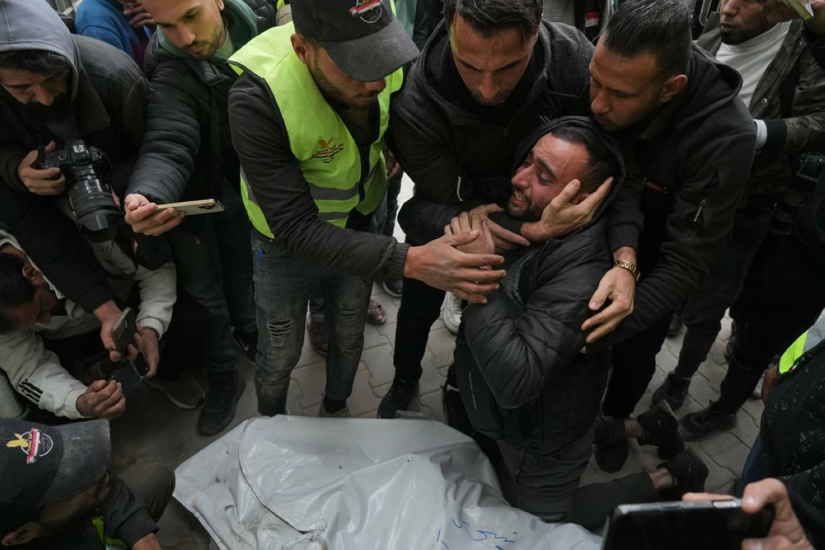 People mourn over the bodies of the Palestinian journalists Abd Shaat and Mohamed Qeshta, who were killed in an Israeli strike on a vehicle, before their funeral at Shifa Hospital, in Gaza City, Wednesday, Jan. 21, 2026. (AP Photo/Jehad Alshrafi)