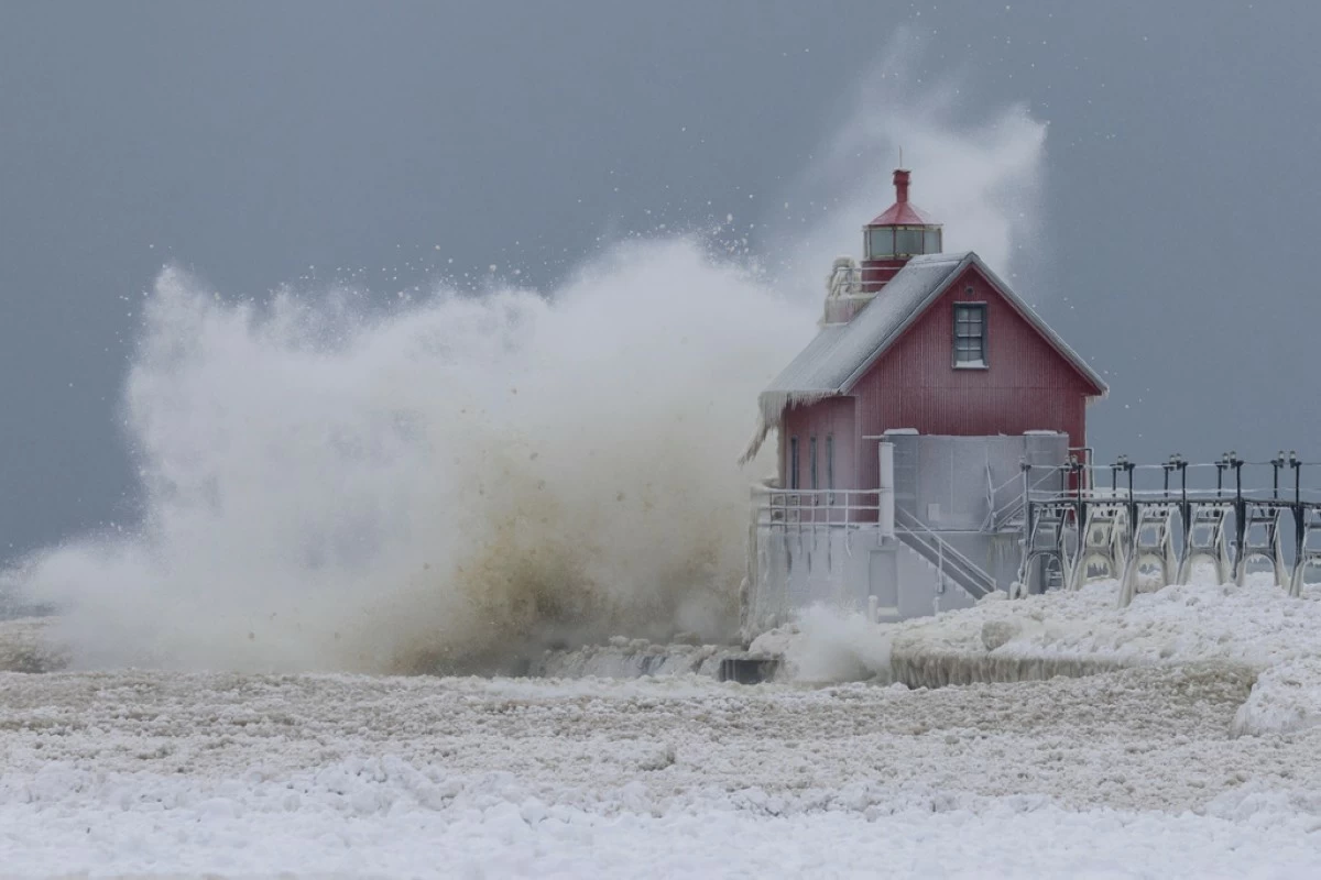 A large wave from Lake Michigan sends ice balls into the air as it crashes into the South Pierhead Outer Light at Grand Haven State Park in Grand Haven, Mich., Monday, Jan. 19, 2026. (Joel Bissell/Kalamazoo Gazette via AP)