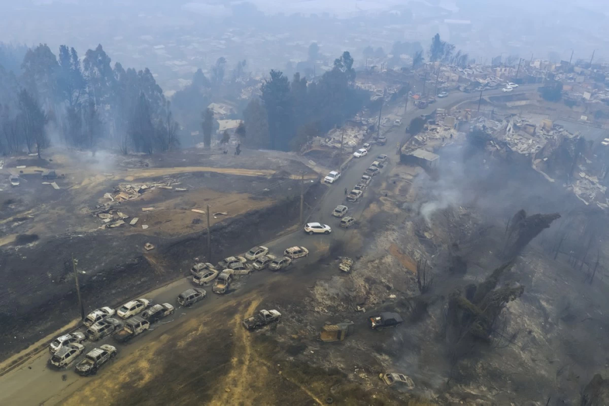 FILE - Damaged vehicles line a road after wildfires swept through residential areas in Lirquen, Chile, Jan. 18, 2026. (AP Photo/Javier Torres, File)