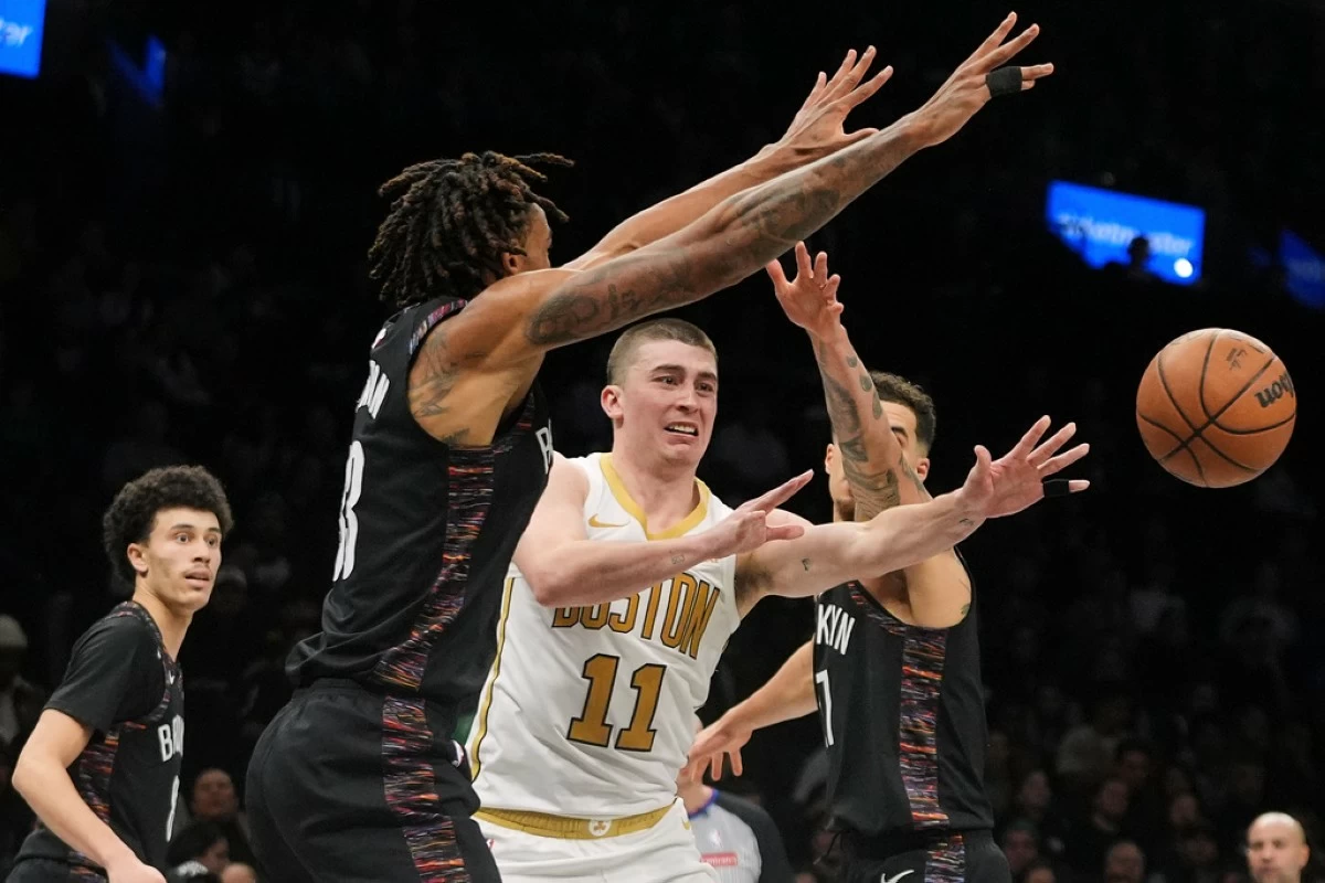 Boston Celtics' Payton Pritchard (11) passes away from Brooklyn Nets' Nic Claxton (33) and Michael Porter Jr. (17) during the second overtime of an NBA basketball game Friday, Jan. 23, 2026, in New York. (AP Photo/Frank Franklin II)