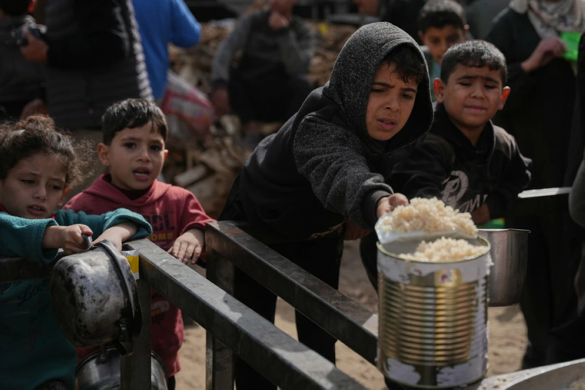 Palestinian children receive donated food at a community kitchen in Nuseirat, in central Gaza Strip, Saturday, Jan. 24, 2026. (AP Photo/Abdel Kareem Hana)