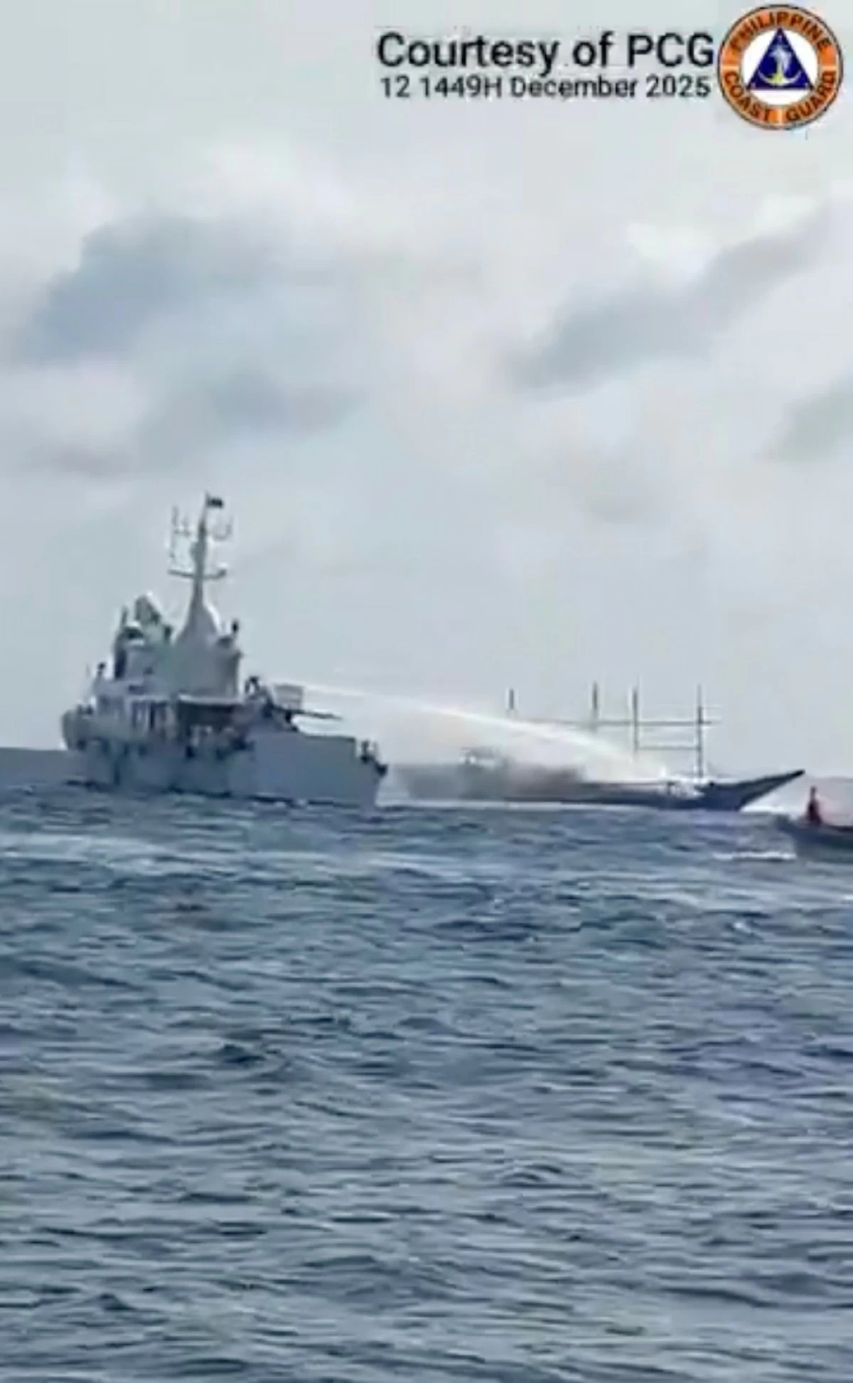 A China Coast Guard vessel fires a water cannon at a much-smaller Filipino fishing boat near Escoda Shoal in the West Philippine Sea on Dec. 12, 2025. Three fishermen were hurt in the incident. (Courtesy of Philippine Coast Guard)