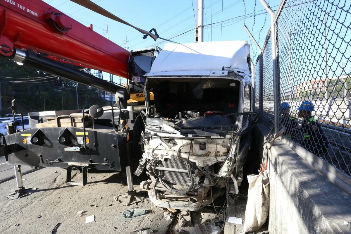 A dump truck crashes into concrete barriers and a concrete post along the eastbound lane of Commonwealth Avenue in Quezon City, then continues moving and comes to a stop between parked heavy equipment and the fence of the MRT-7 construction site on Tuesday, February 3, 2026. Authorities report that the driver allegedly falls asleep while driving, causing the incident. (Photo by Santi San Juan)