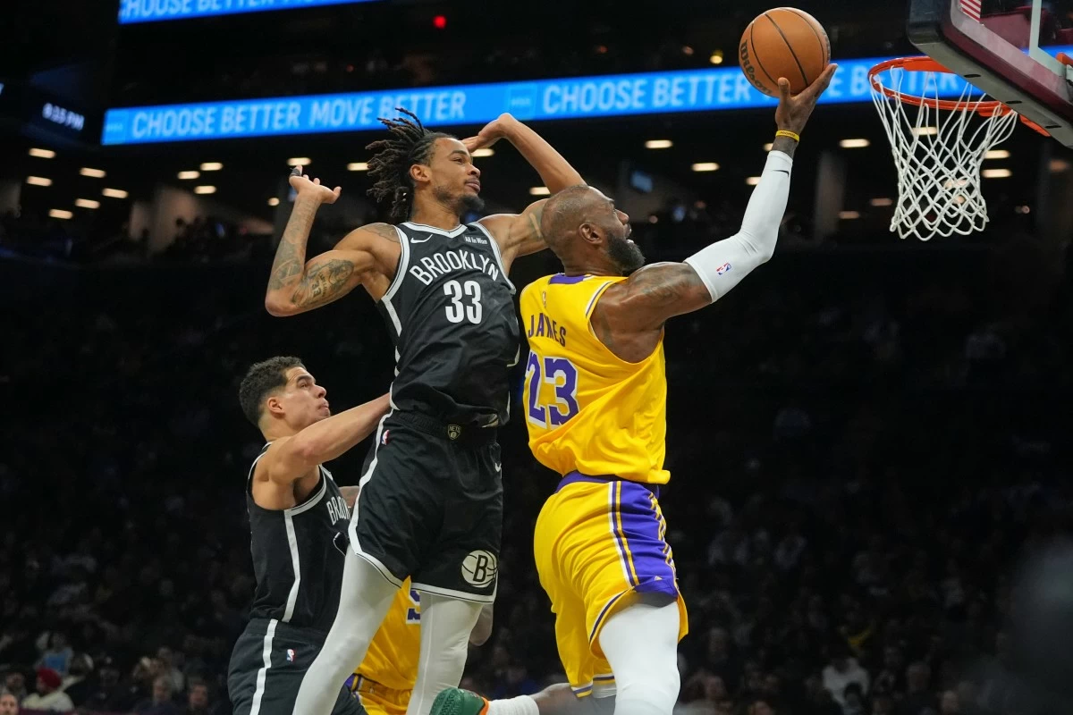 Los Angeles Lakers' LeBron James, right, drives past Brooklyn Nets' Nic Claxton, center, and Michael Porter Jr. during the first half of an NBA basketball game Tuesday, Feb. 3, 2026, in New York. (AP Photo/Frank Franklin II)