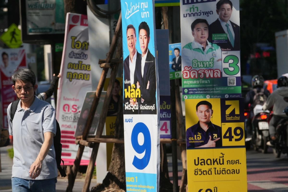 A man walks next to political parties' election campaign posters in Bangkok, Thailand, Wednesday, Feb. 4, 2026. (AP Photo/Sakchai Lalit)