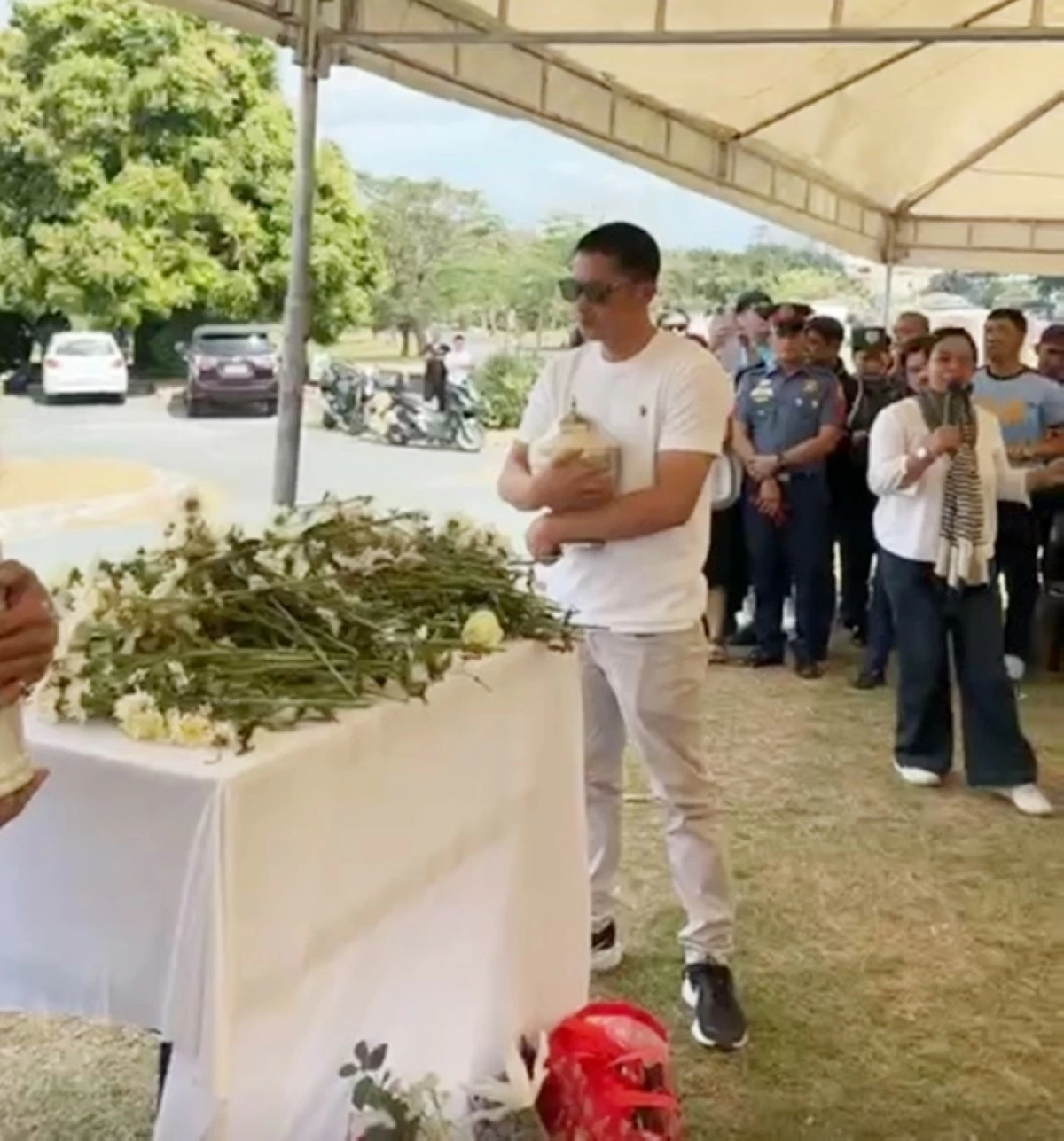 Police Senior Master Sergeant John Mollenido holding the urn containing the cremated remains of his son John Ysmael at Heritage Park in Taguig on Feb. 5 (Screenshot from D. Gab's video on Facebook) 