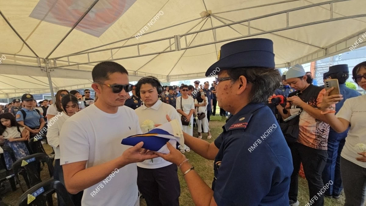 Police Senior Master Sergeant John Mollenido (left) receiving a Philippine flag from a Philippine National Police officer on Feb. 5 at Heritage Park in Taguig (RMFB NCRPO) 

