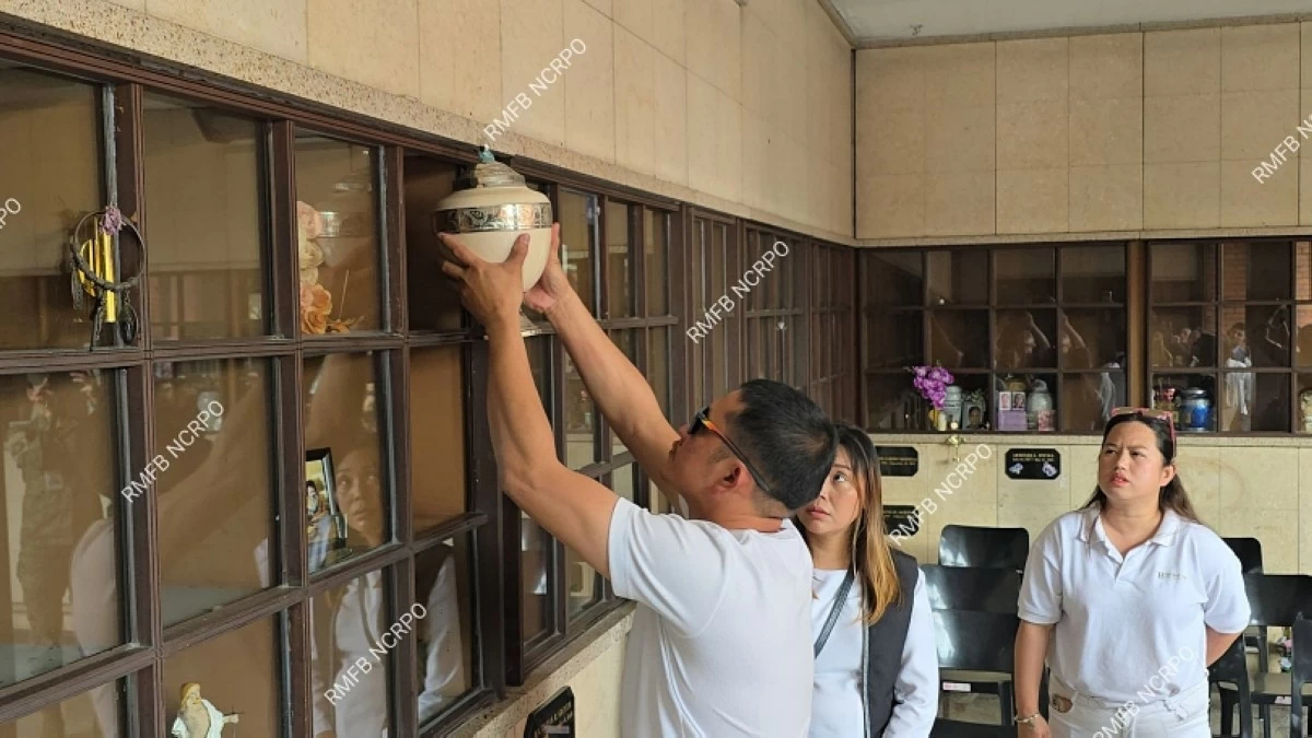 Police Senior Master Sergeant John Mollenido (left) putting the urn containing the cremated remains of his son, John Ysmael, in a niche at a columbarium at Heritage Park in Taguig on Feb. 5 ((RMFB NCRPO) 
