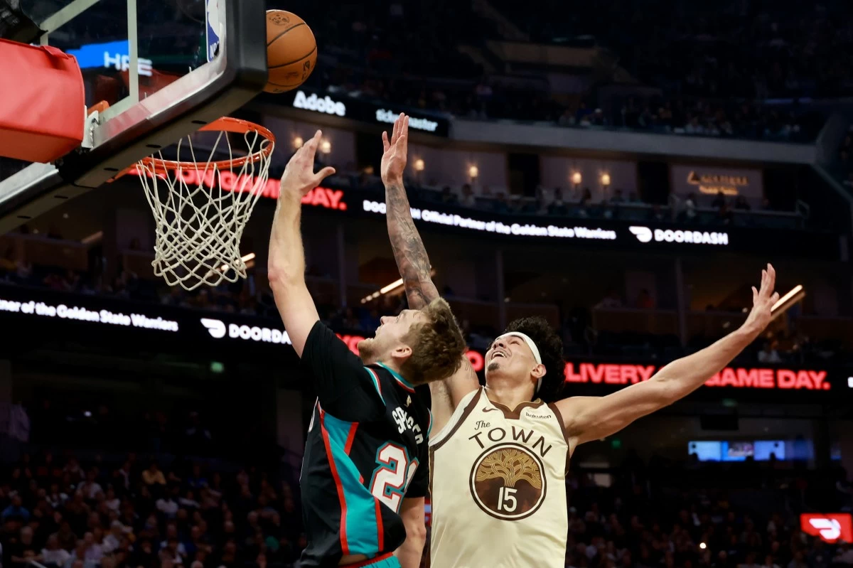 Memphis Grizzlies guard Cam Spencer, left, shoots against Golden State Warriors forward Gui Santos (15) during the first half of an NBA basketball game in San Francisco, Monday, Feb. 9, 2026. (AP Photo/Jed Jacobsohn)