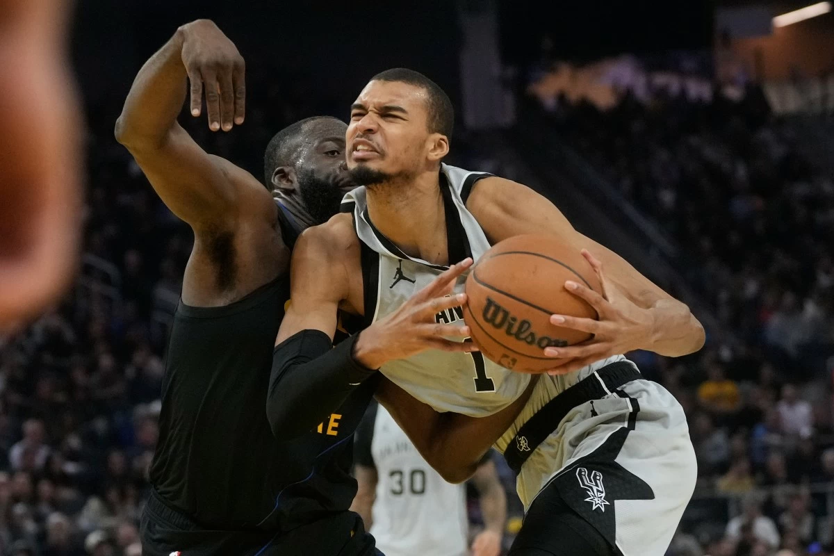 San Antonio Spurs center Victor Wembanyama, right, drives to the basket against Golden State Warriors forward Draymond Green during the first half of an NBA basketball game in San Francisco, Wednesday, Feb. 11, 2026. (AP Photo/Jeff Chiu)