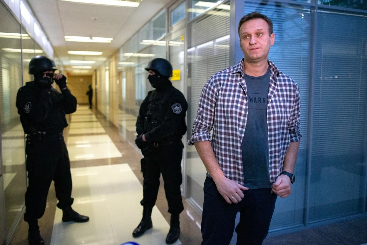 FILE - Russian opposition leader Alexei Navalny speaks to the media in front of security officers standing guard at the Foundation for Fighting Corruption office in Moscow, Russia, Thursday, Dec. 26, 2019. (AP Photo/Alexander Zemlianichenko, File)