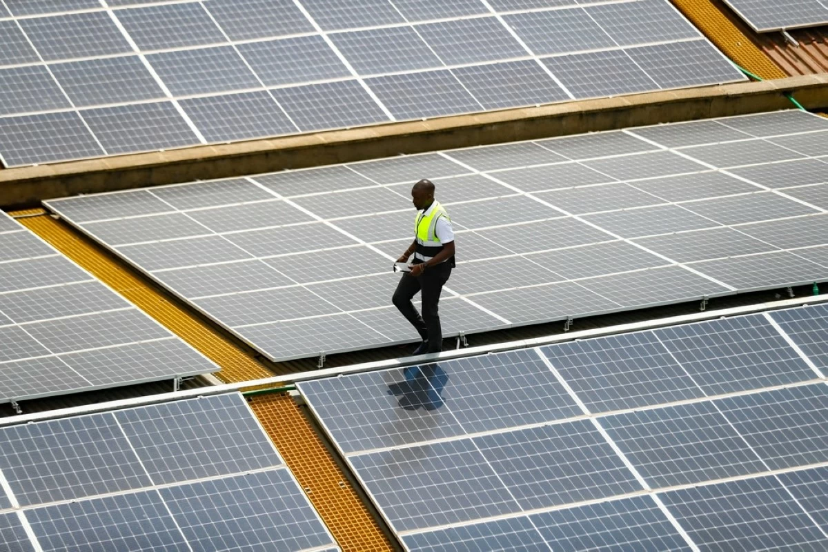 FILE - Mark Munyua, CP solar's technician, examines solar panels on the roof of a company in Nairobi, Kenya, Sept. 1, 2023. (AP Photo/Brian Inganga, File)