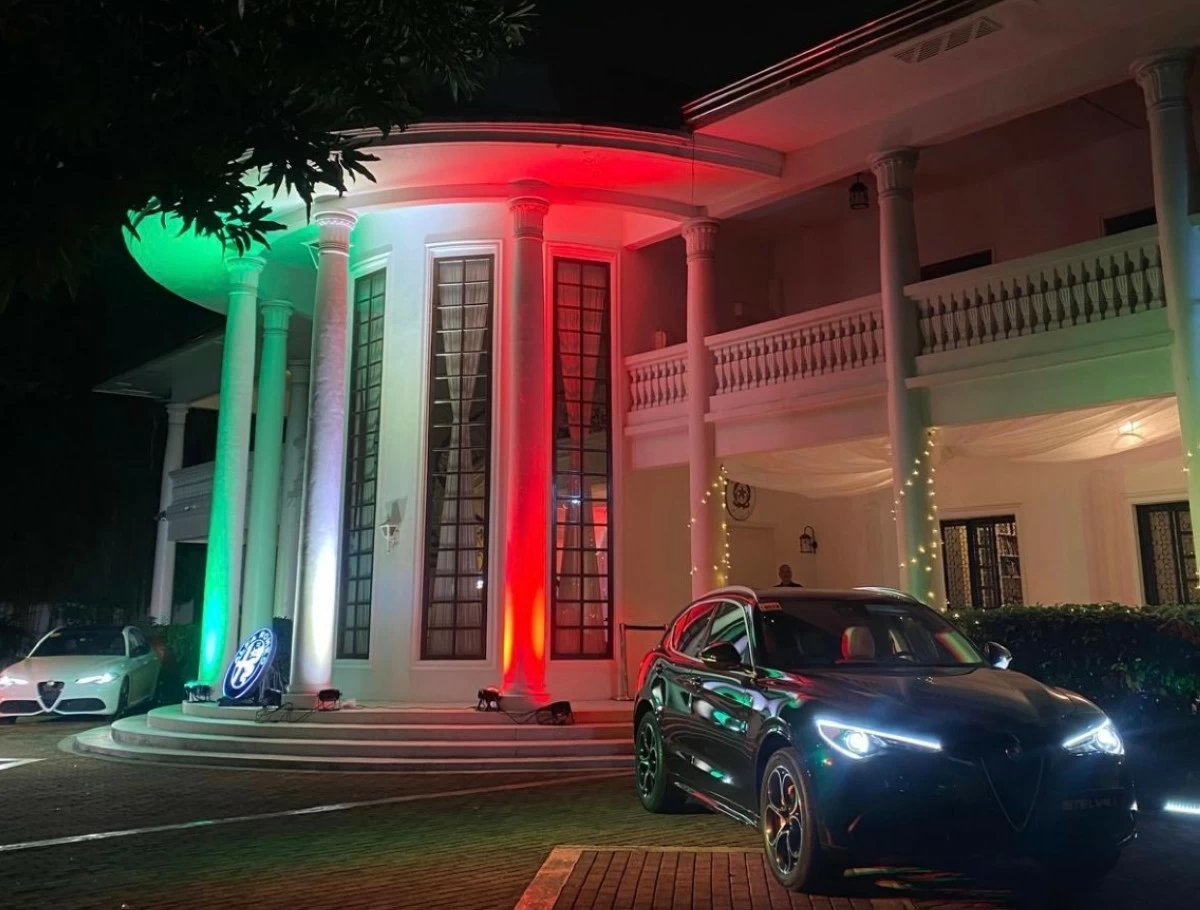 The colors of Italy proudly illuminate the façade of the Italian residence, flanked by Alfa Romeo cars, embodying style and strength
