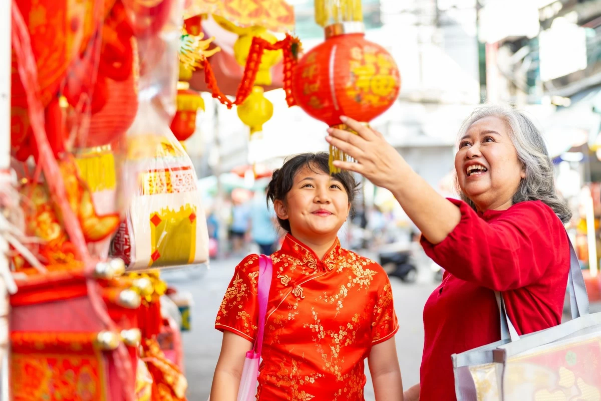 Chinese lunar new year festival and tradition holiday celebration concept. Asian grandmother and grandchild girl buying home decorative ornaments for celebrating Chinese New Year at Chinatown market.