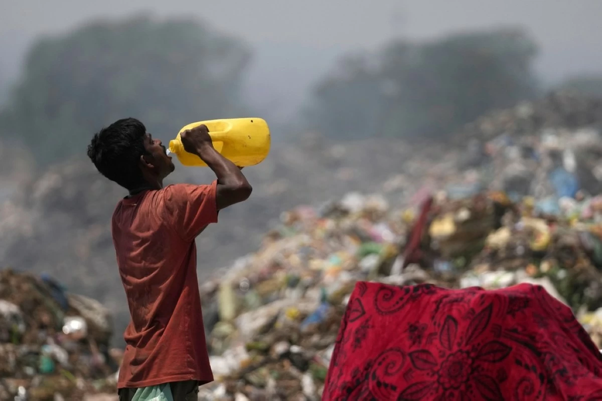FILE - A waste picker drinks water while working during a heat wave at a garbage dump on the outskirts of Jammu, India, Wednesday, June 19, 2024. (AP Photo/Channi Anand, File)