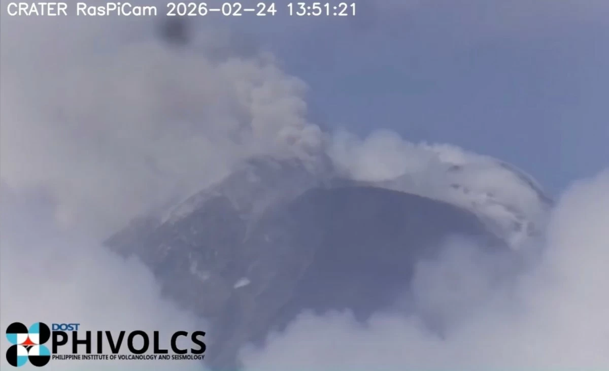 A grayish to brownish ash plume rises about one kilometer above the summit crater of Mayon Volcano on Feb. 24, 2026, drifting west-southwest as captured by the Mayon Volcano Observatory Crater RasPi Camera. The volcano remains under Alert Level 3 amid continuing effusive eruption and volcanic unrest. (Screenshot from Phivolcs Facebook page)