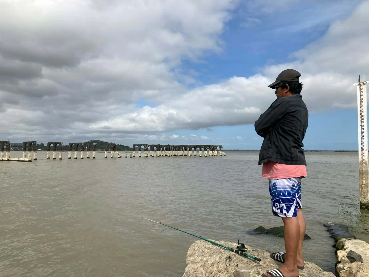 DAILY CATCH A fisherman waits patiently for a catch with the Old Spanish Pier in view.