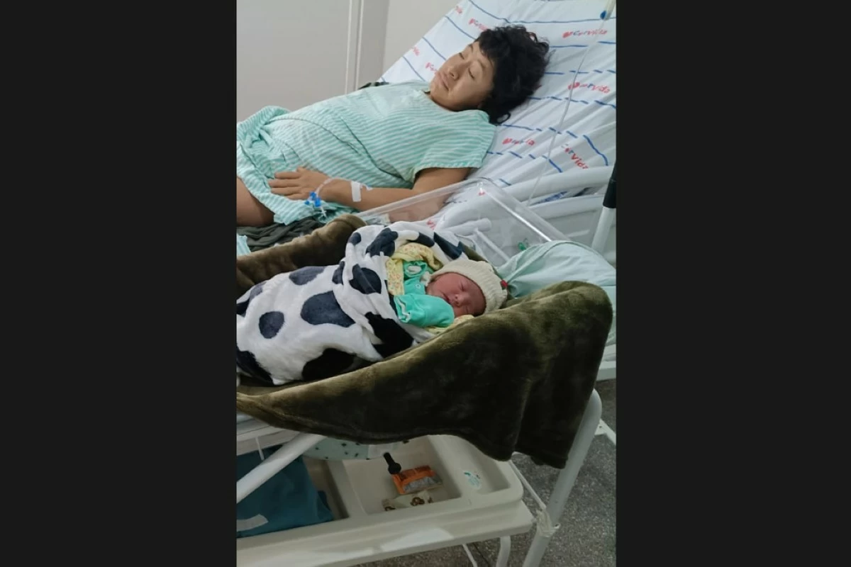 In this photo provided by Funai, Babawru Akuntsu, top, rests beside Akyp, her newborn son, at the Regional Hospital of Vilhena in Vilhena, Rondonia state, Brazil on Dec. 9, 2025, one day after the birth. (Altair Algayer/Funai via AP)
