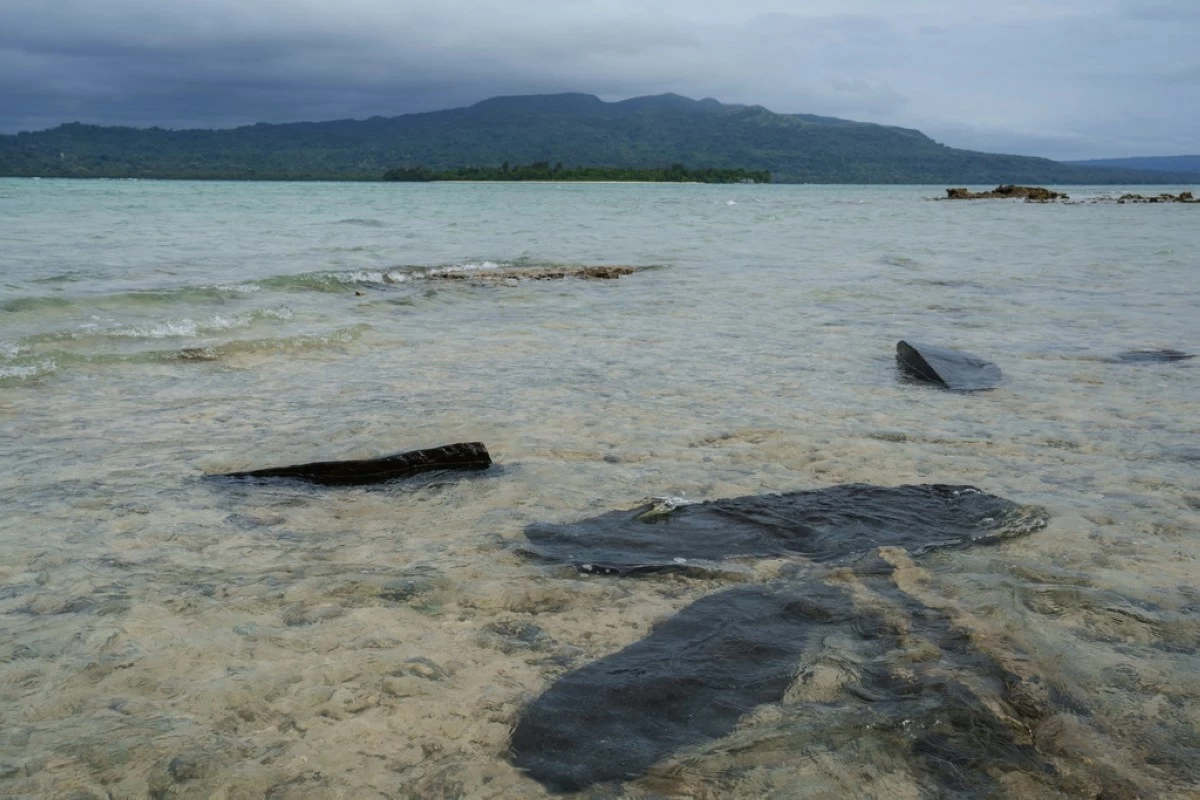 FILE - Gravestones sit submerged in water on Pele Island, Vanuatu, a country heavily affected by rising seas July 18, 2025. (AP Photo/Annika Hammerschlag, File)