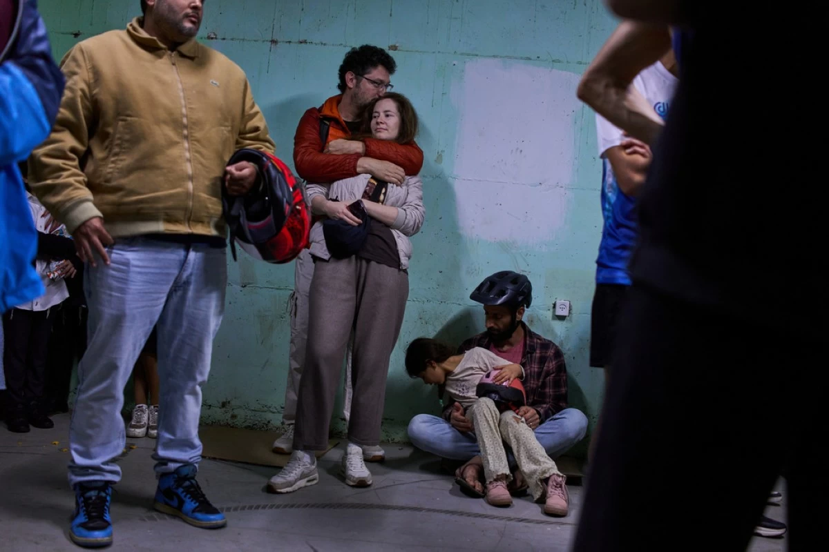 People take shelter as air raid sirens warning of incoming Iranian missiles in Tel Aviv, Israel, Saturday, March 7, 2026. (AP Photo/Oded Balilty)